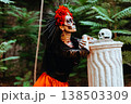 Day of the Dead. Profile portrait of a woman with a wreath of red roses and a skull on a column. Artistic composition 138503309