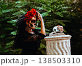 Day of the Dead. Portrait of a woman with a wreath of red roses and a skull on a column. Artistic composition 138503310