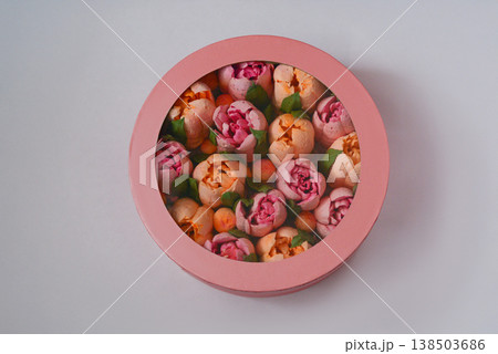 A pink round box with marshmallow flowers on a white background. 138503686