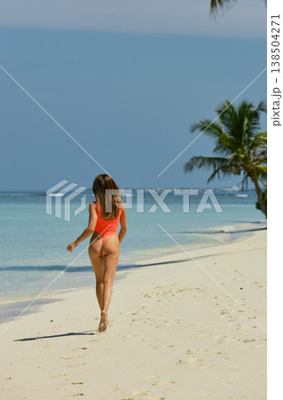 A beautiful tanned girl with an athletic physique in a swimsuit runs on the personal beach of the villa on a sunny day in the Maldives, she is happy and posing A beautiful tanned girl with an athletic physique in a swimsuit runs on the personal beach of the villa on a sunny day in the Maldives, she is happy and posing 138504271