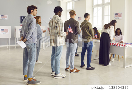Large diverse group of people registering at polling station holding American flags on election day Large diverse group of people registering at polling station holding American flags on election day 138504353