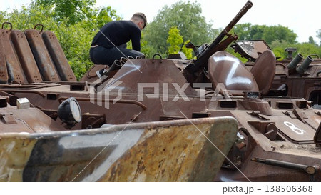 Young man looking at destroyed military equipment of the russian army. Exhibition of rusty and burned-out armored vehicles on ukrainian territory. War between Ukraine and russia. Slow motion 138506368