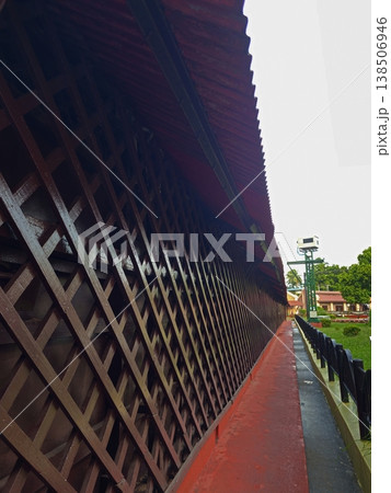 A long, perspective view of a wooden lattice walkway and red-roofed corridor within the Cellular Jail complex. 138506946