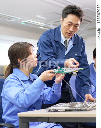 基板を見ながら学ぶ若手と指導する上司の技術研修 138507052