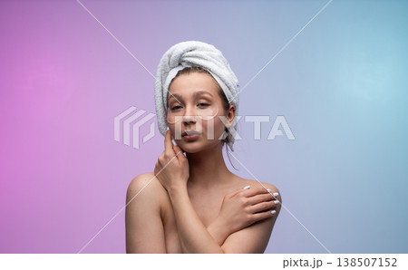 Young woman applying under-eye patches, performing a beauty ritual, wrapped in a bath towel, focusing on wellness and self-care for healthy, hydrated skin 138507152