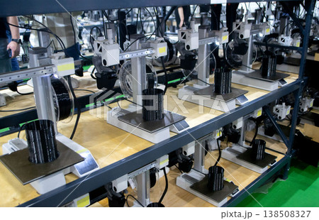 Many 3D printers printing object. 3D printers creating shape from molten plastic flowing out of extruder. 3D printer close up. Working 3D printer in process printing object from molten black plastic Many 3D printers printing object. 3D printers creating shape from molten plastic flowing out of extruder. 3D printer close up. Working 3D printer in process printing object from molten black plastic 138508327