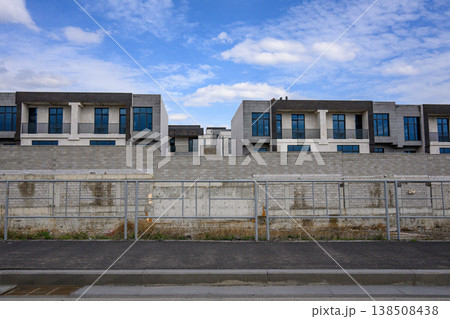 Modern houses behind concrete barrier under blue sky Modern houses behind concrete barrier under blue sky 138508438