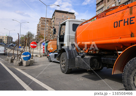 Traffic accident involving fuel tanker and truck in urban area. Orange fuel tanker truck at construction site with road signs Traffic accident involving fuel tanker and truck in urban area. Orange fuel tanker truck at construction site with road signs 138508466