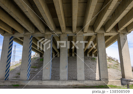 Beneath highway overpass, concrete supports rise into clear blue sky Beneath highway overpass, concrete supports rise into clear blue sky 138508509
