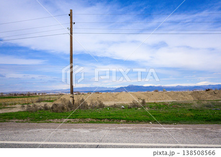 Pole with wires near road under sunny sky 138508566