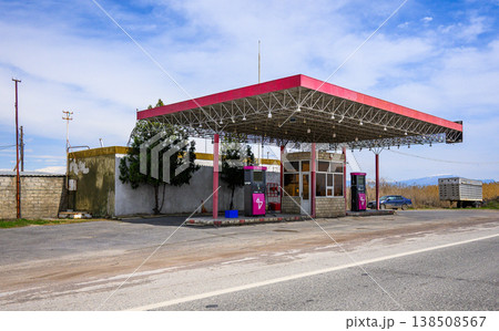 Abandoned gas station under bright sky with faded red roof Abandoned gas station under bright sky with faded red roof 138508567