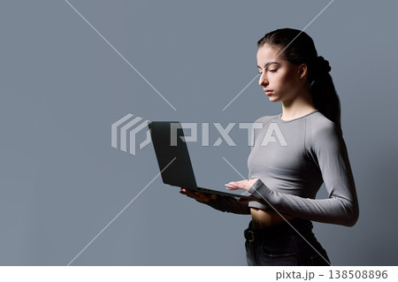 Profile portrait of serious teenage girl using laptop on gray background Profile portrait of serious teenage girl using laptop on gray background 138508896