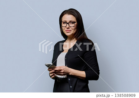 Portrait mature woman with smartphone on grey studio background 138508909
