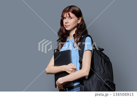 Portrait of beautiful girl teenage student with backpack, laptop on gray background 138508913