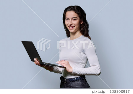 Portrait of smiling teenage girl using laptop on gray background 138508917