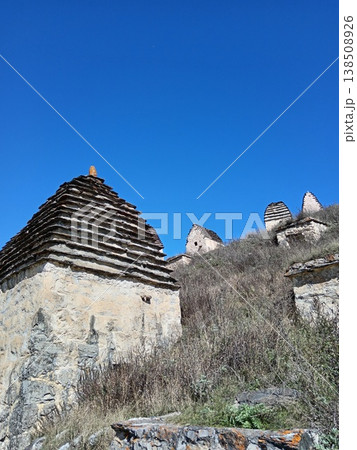 Dargavs City of the Dead necropolis, North Ossetia, Russia. Historic burial site with rows of white crypts stretching across the green landscape Dargavs City of the Dead necropolis, North Ossetia, Russia. Historic burial site with rows of white crypts stretching across the green landscape 138508926