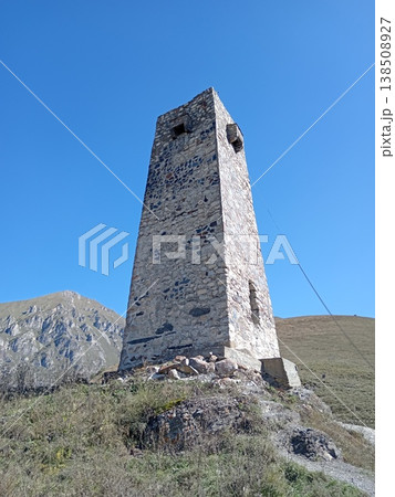 Alan Ancestral Tower, City of the Dead, Dargavs Necropolis, North Ossetia, Russia. Ancient stone tower standing among white crypts in the mountain valley Alan Ancestral Tower, City of the Dead, Dargavs Necropolis, North Ossetia, Russia. Ancient stone tower standing among white crypts in the mountain valley 138508927