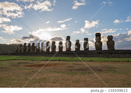 Majestic moai statue stands on rapa nui easter island evoking mysterious awe under bright peaceful sky with white cloud during an inspiring sunrise over grassy ancient landscape Majestic moai statue stands on rapa nui easter island evoking mysterious awe under bright peaceful sky with white cloud during an inspiring sunrise over grassy ancient landscape 138509615