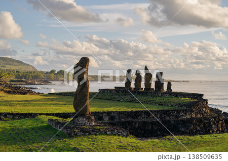 Majestic moai statue stands with calm stoic expression on green coast of ancient easter island rapa nui overlooking serene ocean under cloudy sky evoking deep sense of mystery 138509635
