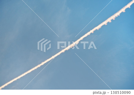 Airplane white pink condensation trail (also known as chemtrails in conspiracy theory)  painted diagonally over clear morning sky 138510090