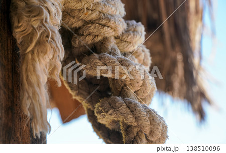 Thick natural fiber rope knot tied at beach hut, closeup detail 138510096