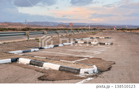 Parking lot spaces at rest area near main highway, desert landscape background 138510123