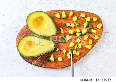 Yellow green avocado pulp cut to small pieces on wooden cutting board, knife blade near, view from above Yellow green avocado pulp cut to small pieces on wooden cutting board, knife blade near, view from above 138510171