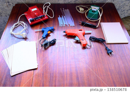 craft tools including glue guns and paper on a wooden table 138510678