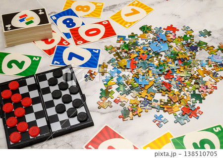 game set with puzzles, checkers and cards laid out on a light table surface game set with puzzles, checkers and cards laid out on a light table surface 138510705