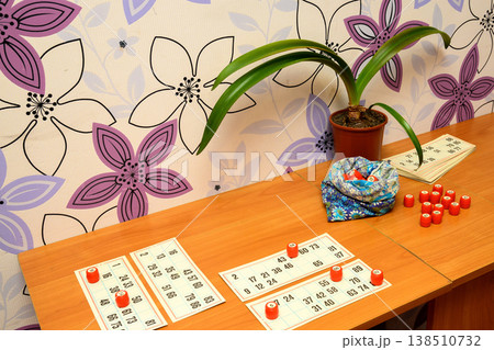 lotto cards and red barrels on a table next to a pouch and a plant lotto cards and red barrels on a table next to a pouch and a plant 138510732