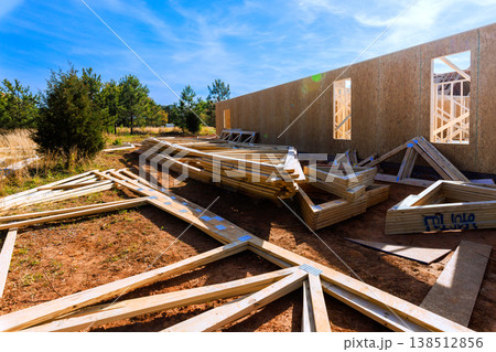 Wooden beams litter construction site as building wall begins to rise under construction 138512856