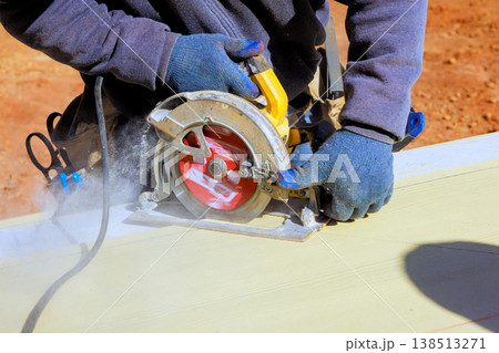 Contractor uses circular saw to cut piece of wood at construction site during build progresses Contractor uses circular saw to cut piece of wood at construction site during build progresses 138513271