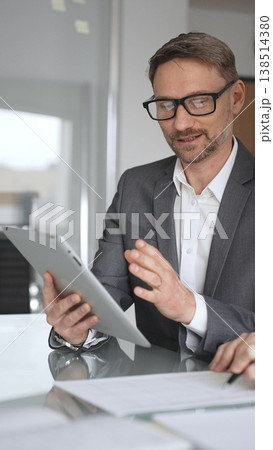 Business colleagues collaborating and discussing important company strategy and planning, a man explaining while a woman takes notes during a productive corporate meeting, vertical view 138514380