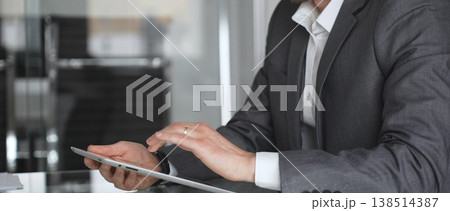 Businessman in a modern office using a digital tablet, managing data and corporate tasks, embracing mobile technology for productivity and efficient communication during a meeting, close up. Businessman in a modern office using a digital tablet, managing data and corporate tasks, embracing mobile technology for productivity and efficient communication during a meeting, close up. 138514387