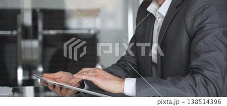 Businessman in a modern office using a digital tablet, managing data and corporate tasks, embracing mobile technology for productivity and efficient communication during a meeting, close up. Businessman in a modern office using a digital tablet, managing data and corporate tasks, embracing mobile technology for productivity and efficient communication during a meeting, close up. 138514396