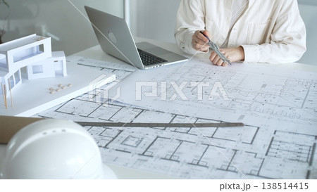 Architect working on a new building project, using a laptop to review digital blueprints and architectural models, creating modern house designs for urban development planning 138514415
