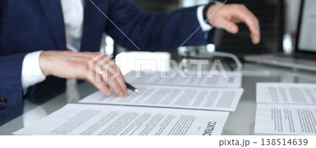 Business person reviewing a contract document, signing an agreement in an office setting, hands holding a pen, close up on the legal papers and corporate deal negotiations Business person reviewing a contract document, signing an agreement in an office setting, hands holding a pen, close up on the legal papers and corporate deal negotiations 138514639