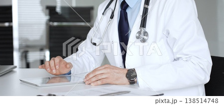 Doctor using a modern digital tablet for patient information and online consultation in a professional clinic environment. Medicine, healthcare and science concept 138514748