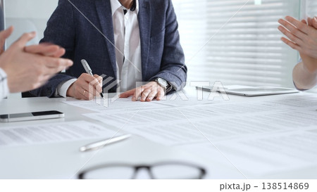 Business professional hand holding a pen, signing a document on a white desk during an important boardroom meeting, finalizing a partnership or legal agreement Business professional hand holding a pen, signing a document on a white desk during an important boardroom meeting, finalizing a partnership or legal agreement 138514869