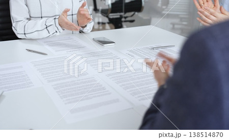 Business partners discussing and signing a legal contract during an important meeting, with hands showing agreement and successful negotiation in a formal office setting 138514870