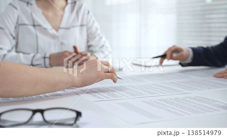Business people collaborating at a conference table, reviewing paperwork, sharing ideas, and reaching a mutual agreement during a professional meeting or consultation 138514979