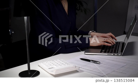 Woman's hands typing on laptop at office desk, working late night with calculator and financial documents. Audit and taxes in business Woman's hands typing on laptop at office desk, working late night with calculator and financial documents. Audit and taxes in business 138515084