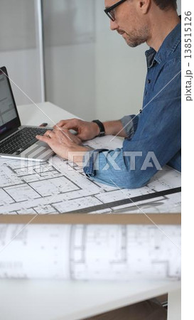 Architect drawing and measuring blueprints on a desk, creating detailed floor plans and designs for construction projects, demonstrating precision and expertise in architectural planning 138515126