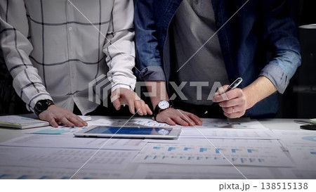 Business professionals analyzing financial data with charts and graphs on a tablet and paper, collaborating on market strategy and corporate growth planning in an office setting 138515138