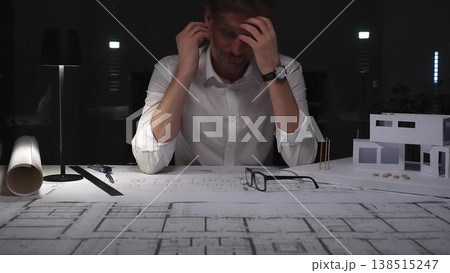 Architect experiencing burnout and stress, working late at night in a dark office with building models and blueprints. Architect experiencing burnout and stress, working late at night in a dark office with building models and blueprints. 138515247