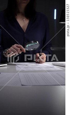 Woman examining tax forms and financial statements at desk, using calculator and magnifying glass to verify figures and audit records. Audit and taxes theme in business Woman examining tax forms and financial statements at desk, using calculator and magnifying glass to verify figures and audit records. Audit and taxes theme in business 138515327