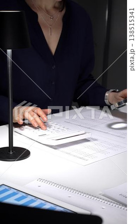 Person checking financial documents and numbers with a magnifying glass, analyzing business data for budgeting and taxes at night. Audit and taxes in business Person checking financial documents and numbers with a magnifying glass, analyzing business data for budgeting and taxes at night. Audit and taxes in business 138515341