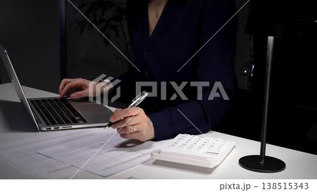 Woman's hands typing on laptop at office desk, working late night with calculator and financial documents. Audit and taxes in business 138515343