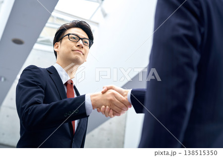 ビジネス提携や契約の成立を象徴する、笑顔で握手をする日本人ビジネスマン 138515350
