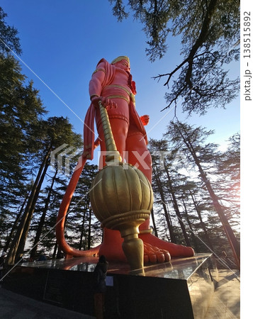 Towering Hanuman statue at Jakhu Temple seen from below, framed by tall pine trees, conveying spiritual significance and the scale of the hilltop monument. 138515892